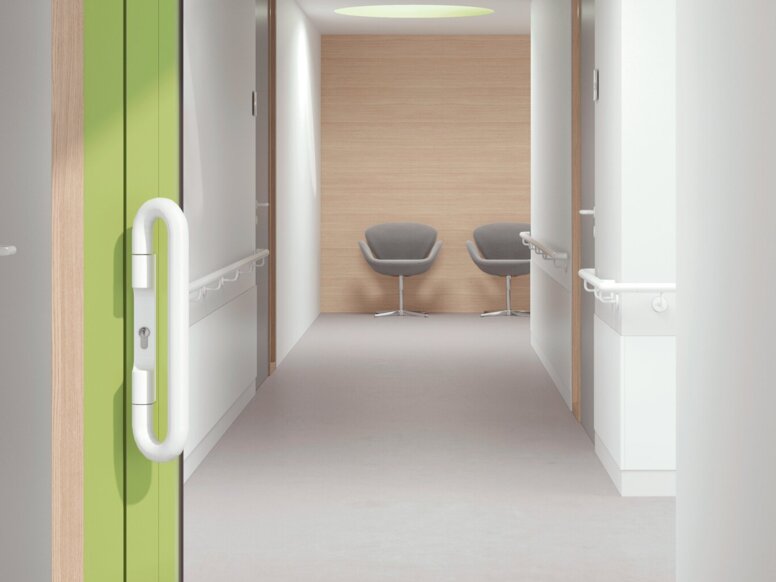 HEWI ENTRO handrails A glass door with a green frame and a white door handle in a white corridor
