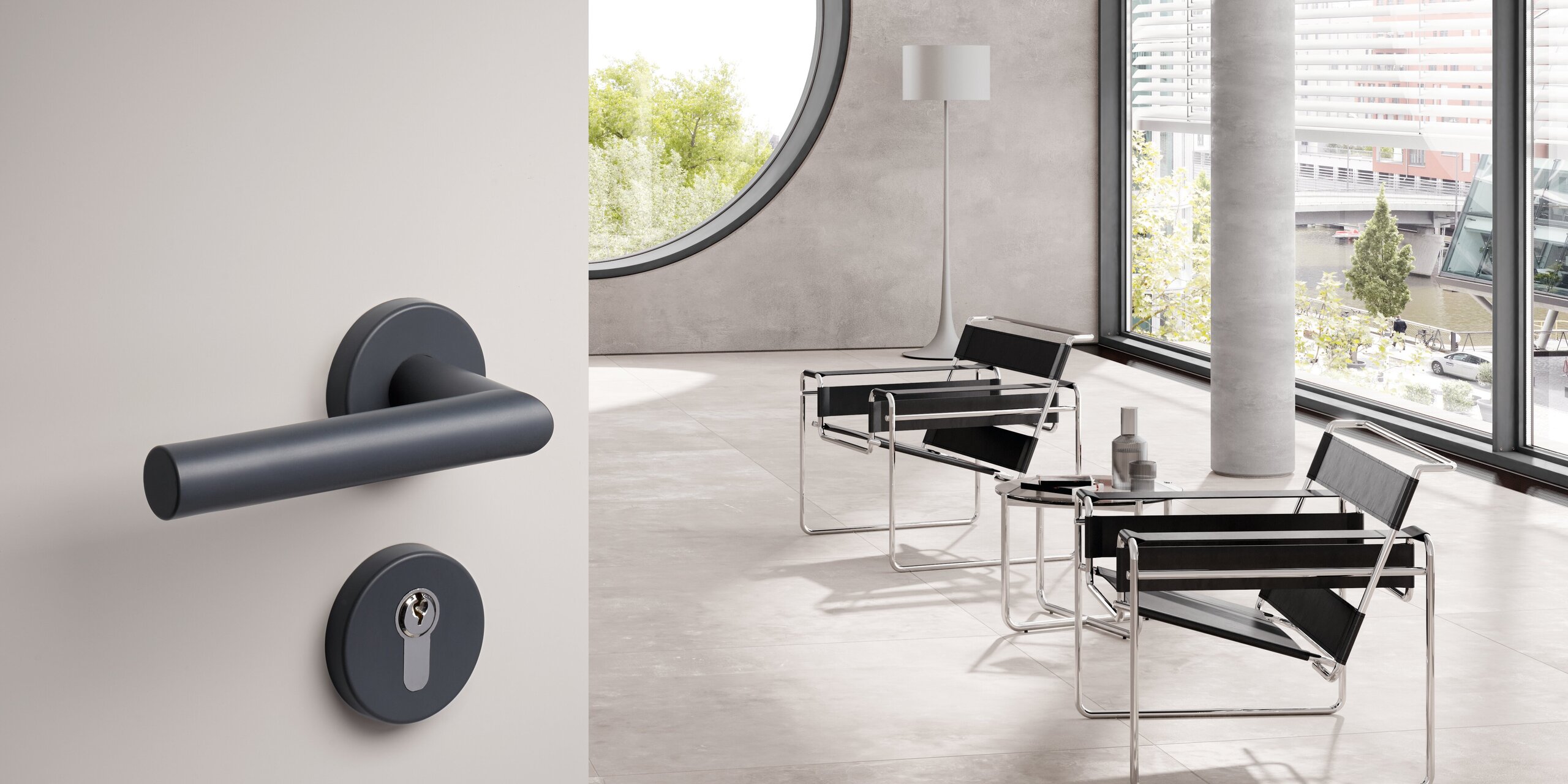 Dark grey lever handle with a round rose and matching keyhole escutcheon on a light grey door, with black armchairs and large windows in the bright room beyond