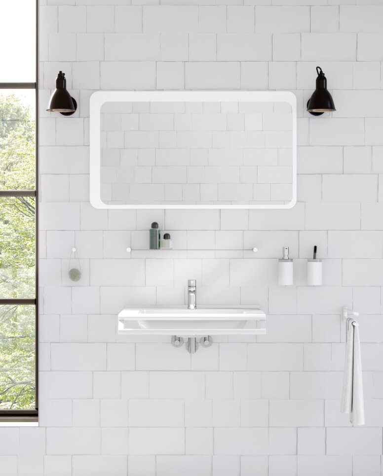 A washbasin with a side-mounted towel holder beneath a rectangular mirror with integrated lighting in the wash area, set against a white tiled wall