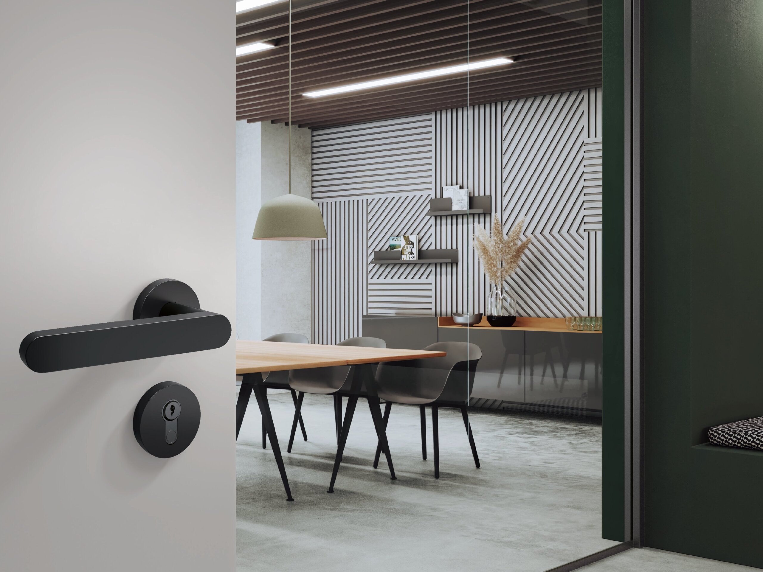A black door handle with a round rose and a matching lock cylinder fitted to a light grey door; behind it is a meeting room