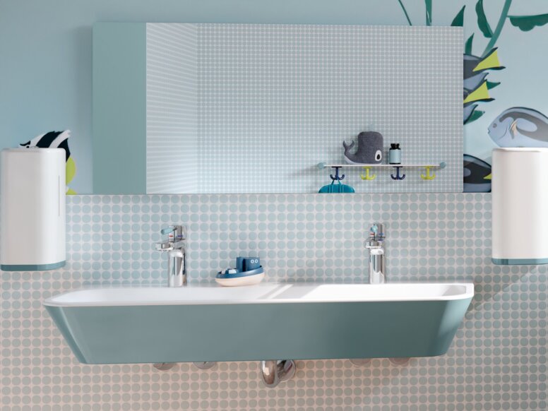 HEWI Range 801 ICONIC Interior A blue children’s washbasin made of mineral composite, with soap dispensers and a mirror above it, next to which is a WC area