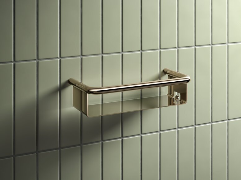 Shower basket with a brass-coloured PVD coating against a backdrop of light green tiles