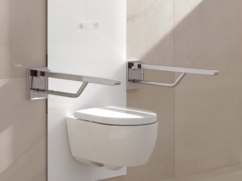 Weißes, wandhängendes WC-Modul mit zwei klappbaren Haltegriffen links und rechts an beiger Fliesenwand