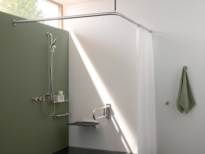 HEWI Range 805 Interior A white shower curtain hanging from a ceiling-mounted rail in the shower area, with a hinged seat and a support rail on the wall, in white and green