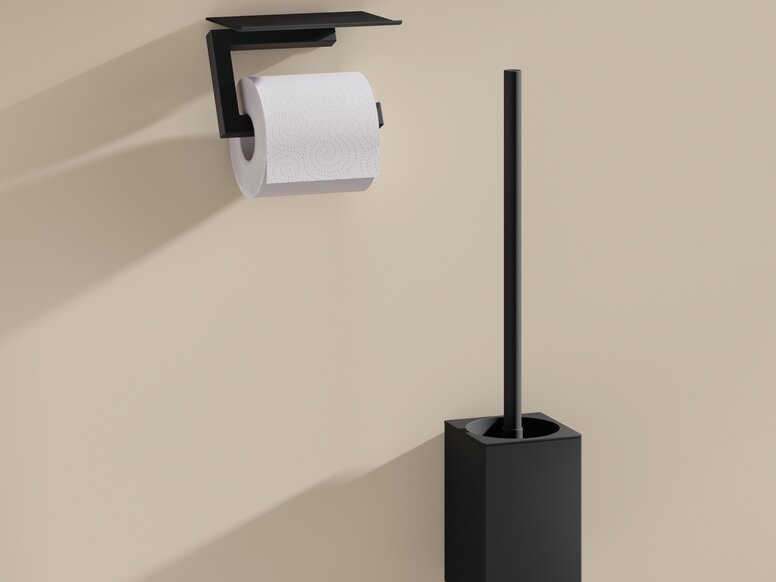 HEWI System 900Q toilet brush unit and toilet roll holder Black powder-coated toilet roll holder with a shelf and a black toilet brush with a holder on a beige wall