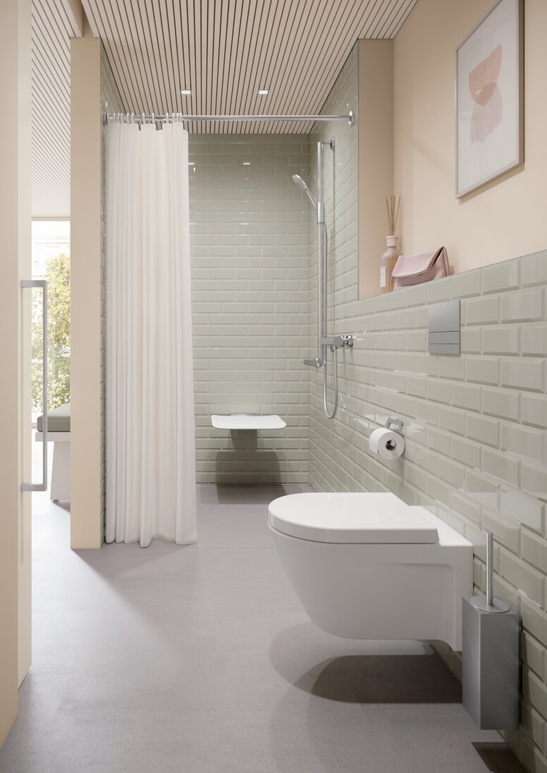 HEWI System 900Q Interior A hinged seat in a shower area with a rail with shower head holder, in front of which is a WC area with a toilet brush and a toilet roll holder