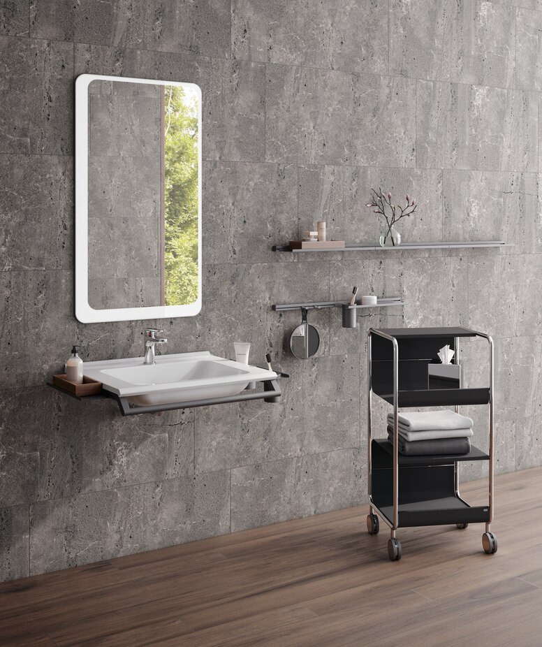 Washbasin with a side shelf and a front support rail, above which is a rectangular mirror with rounded corners in the wash area