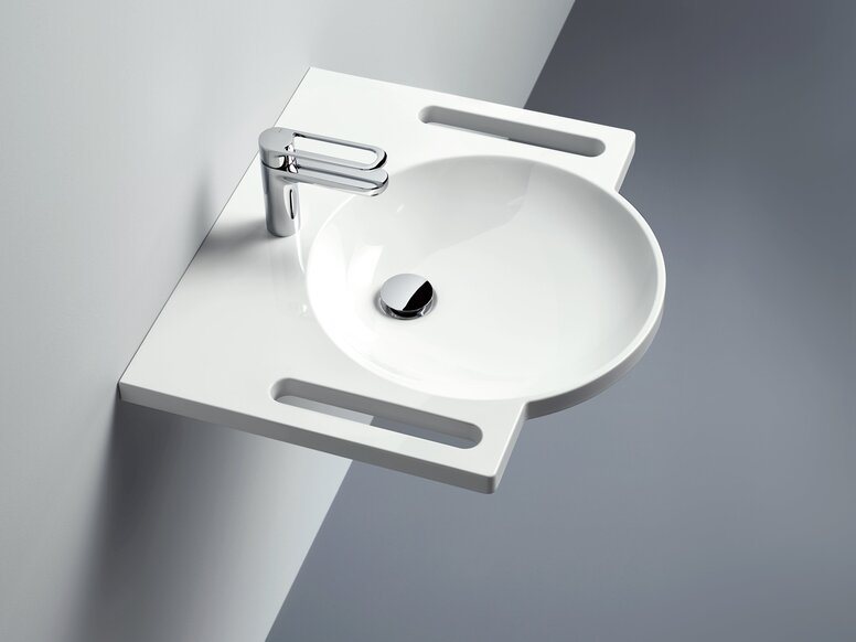 HEWI S950 washbasin Wall-mounted round washbasin made of mineral composite with integrated handles on both sides and a tap against a light grey wall