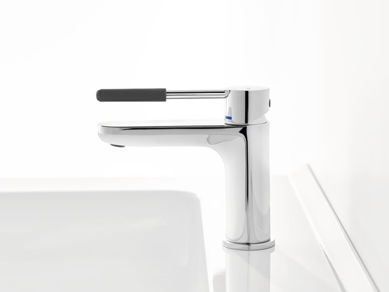Chrome-plated tap with a long lever handle and dark grey grip sleeve on a white washbasin against a white background