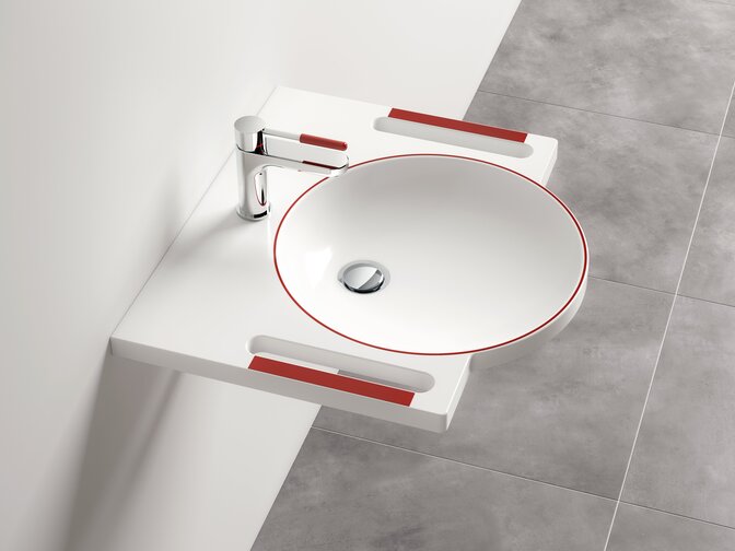White washbasin with a round bowl, red contrast elements, recessed side grips and a chrome-plated tap