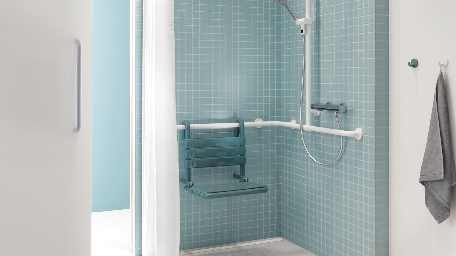 Shower area of a patient bathroom in blue and white with a view through a sliding door